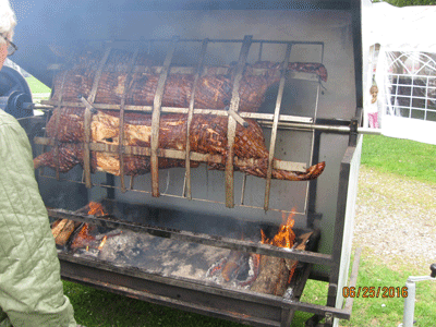 Roast 80 kg of pork over a fire in a giant grill